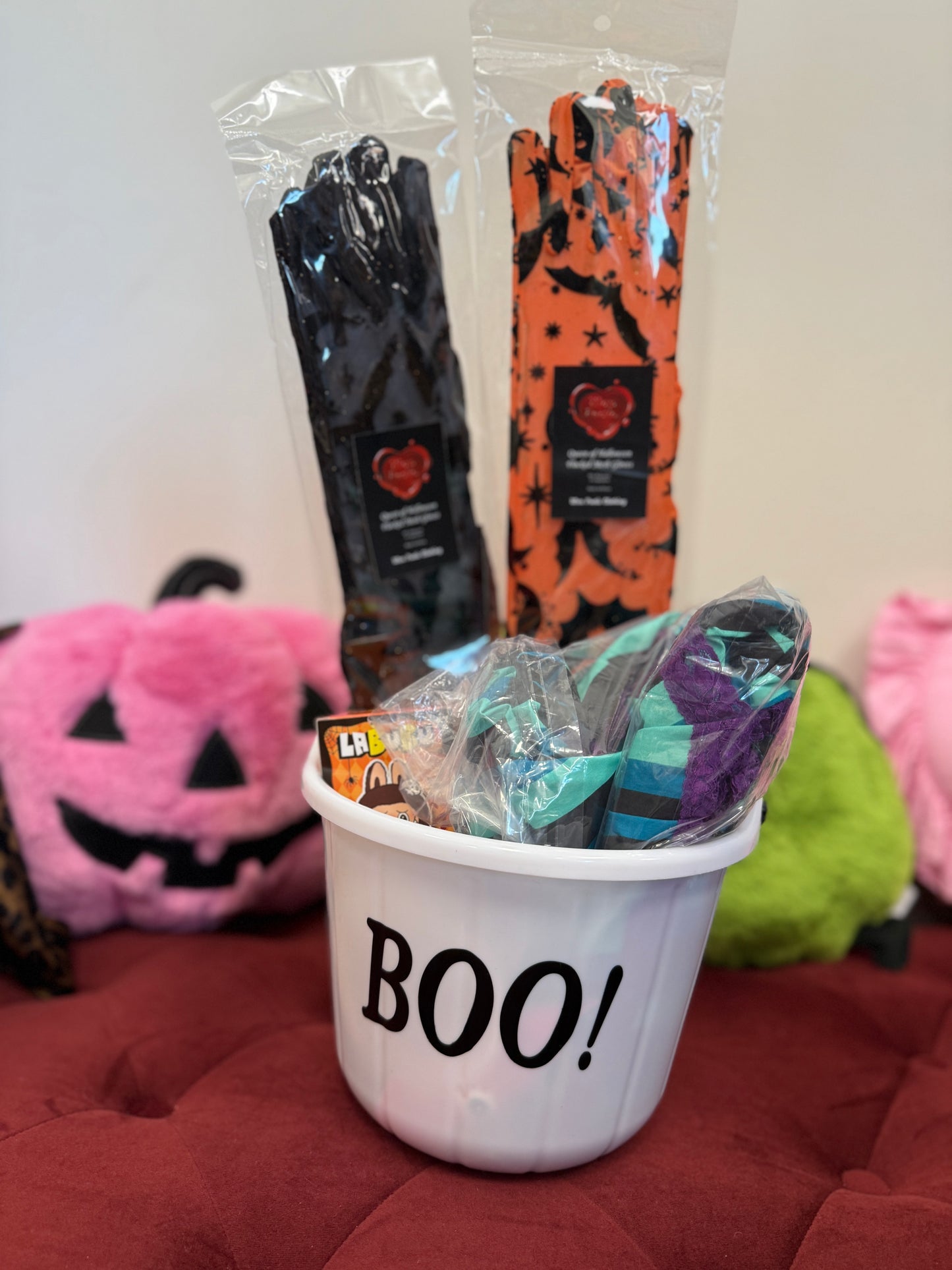 Halloween-themed items including a bucket labeled 'BOO!', candy, and wrapped treats on a red surface.