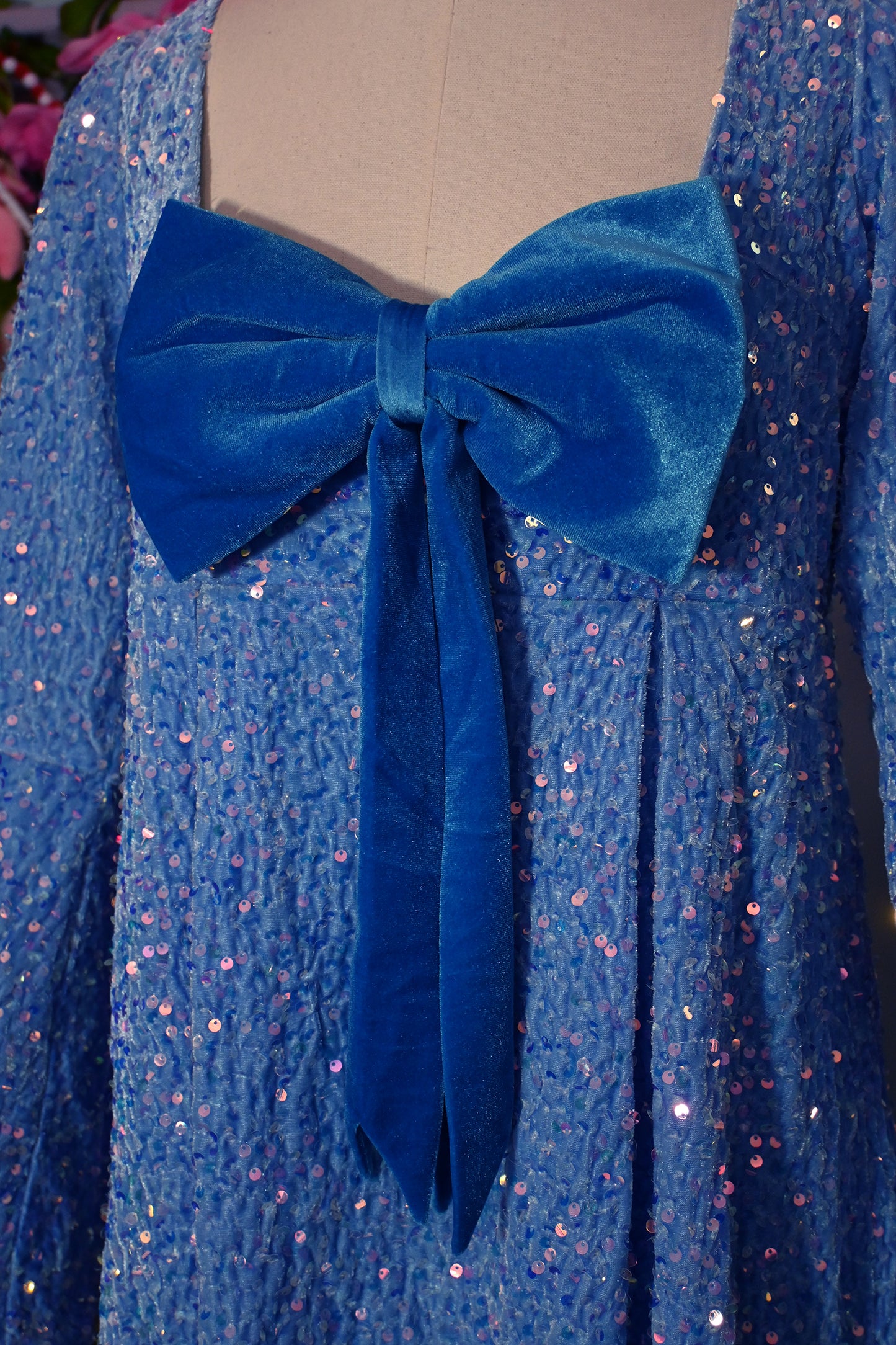 Close-up of Priscilla 60's inspired blue velvet mini dress with sparkly sequins and removable bow.