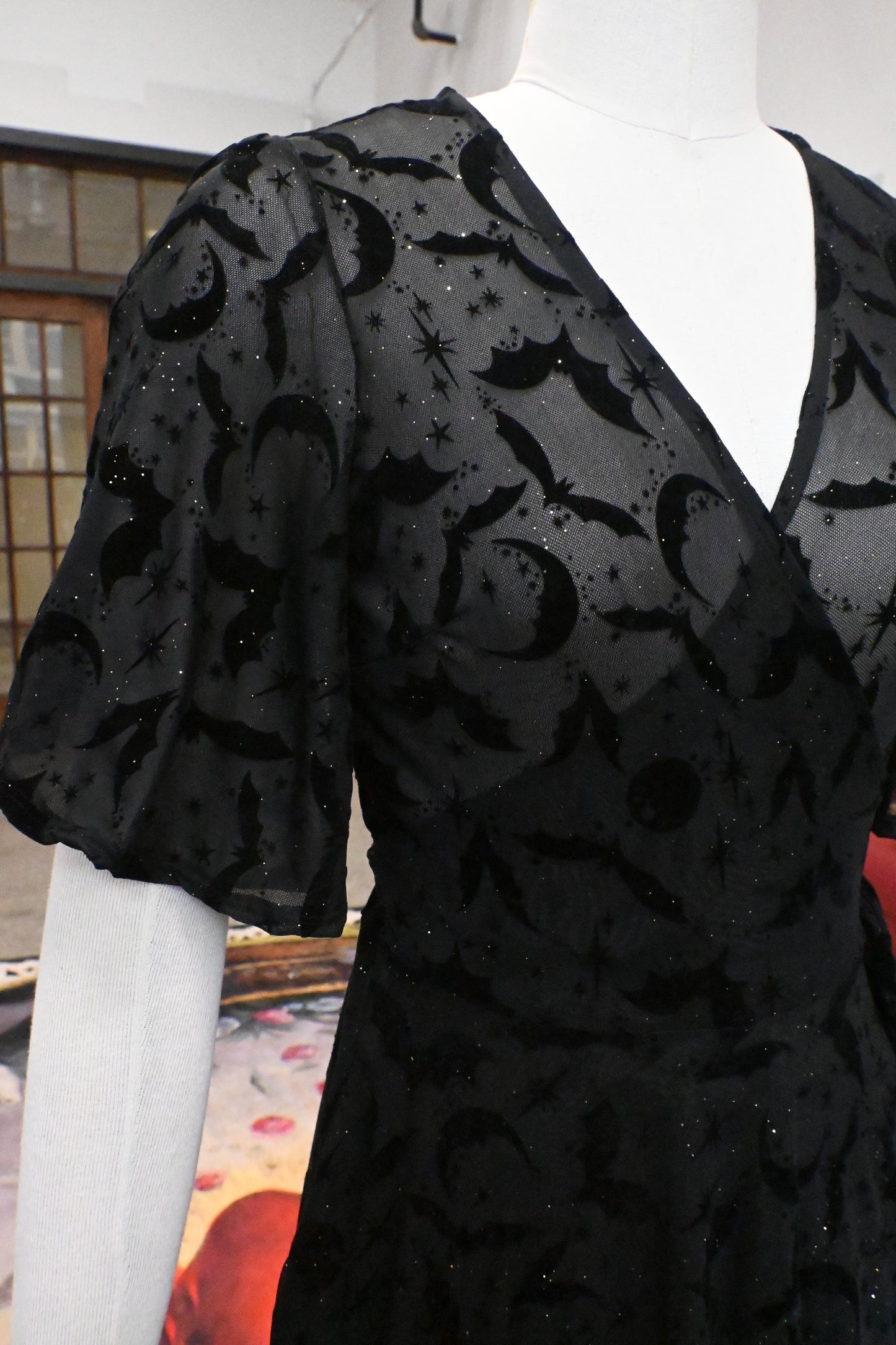 Close-up of the Lydia Wrap Dress featuring flocked bats, moons, stars, and soft flutter sleeves in black mesh.