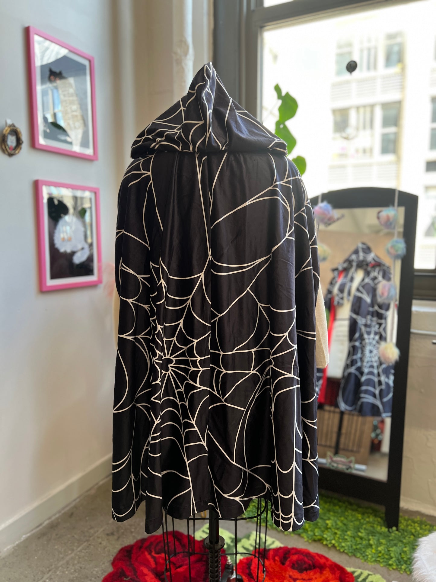 Florence Hooded Cape in spiderweb print, showcasing the back view with oversized hood and dramatic design.