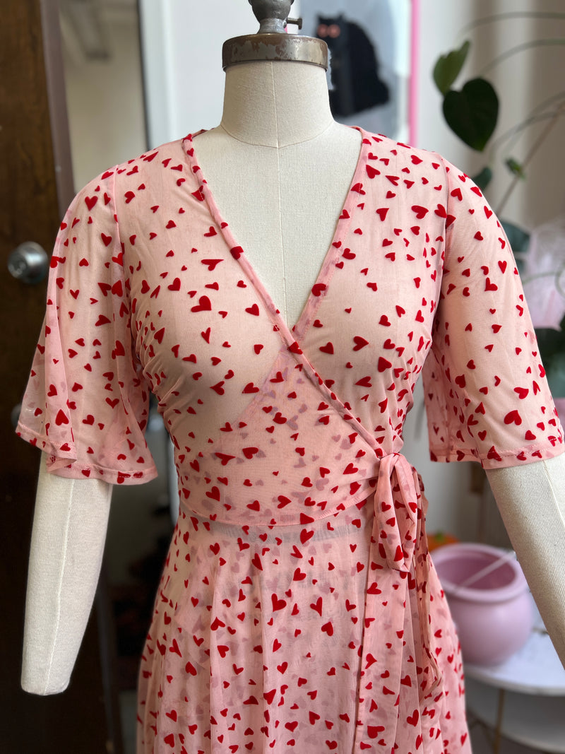 Pink mesh maxi wrap dress with red flocked hearts, featuring pockets, perfect for Valentine's Day.