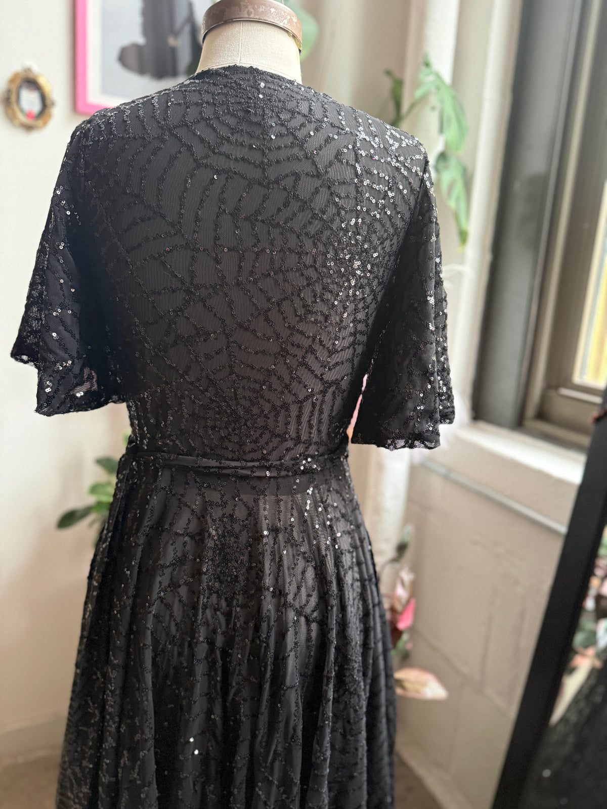 A floor length, black sequin gown, a true wrapped dress style with sequence, spiderweb thrown throughout