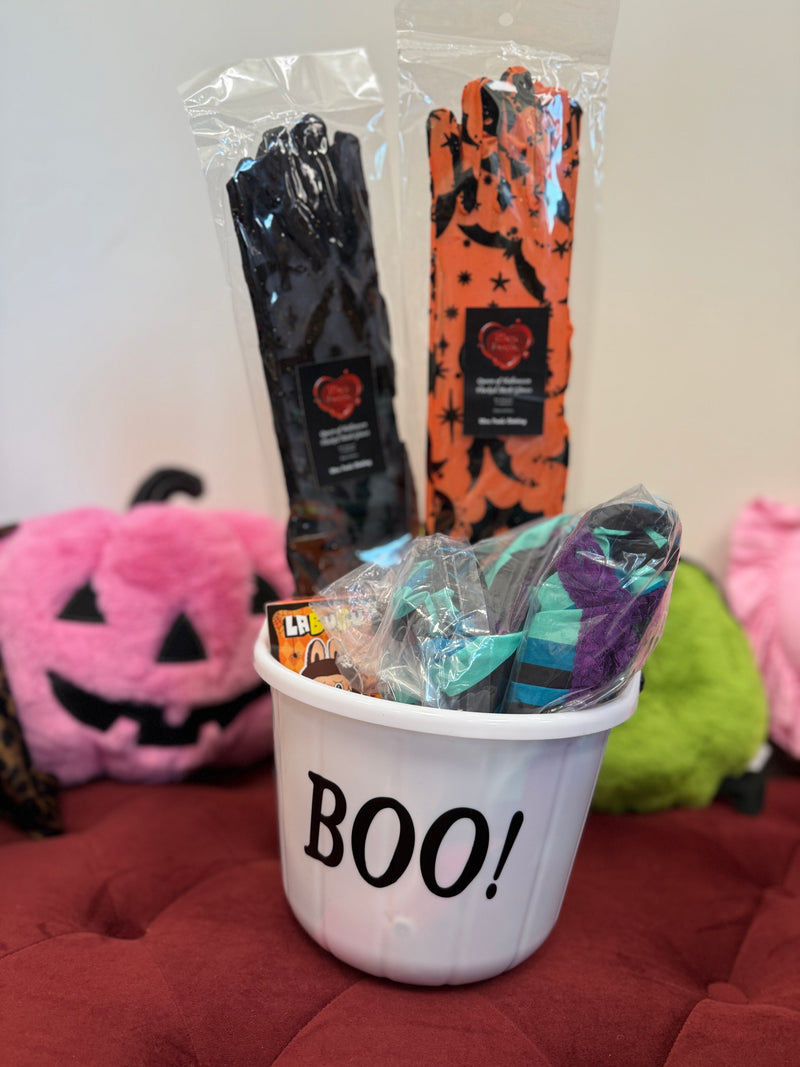 Halloween-themed items including a bucket labeled 'BOO!', candy, and wrapped treats on a red surface.