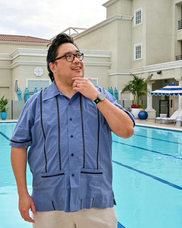 Man wearing a navy working blues cocktail shirt by the pool, showcasing its stylish oversized fit and pockets.