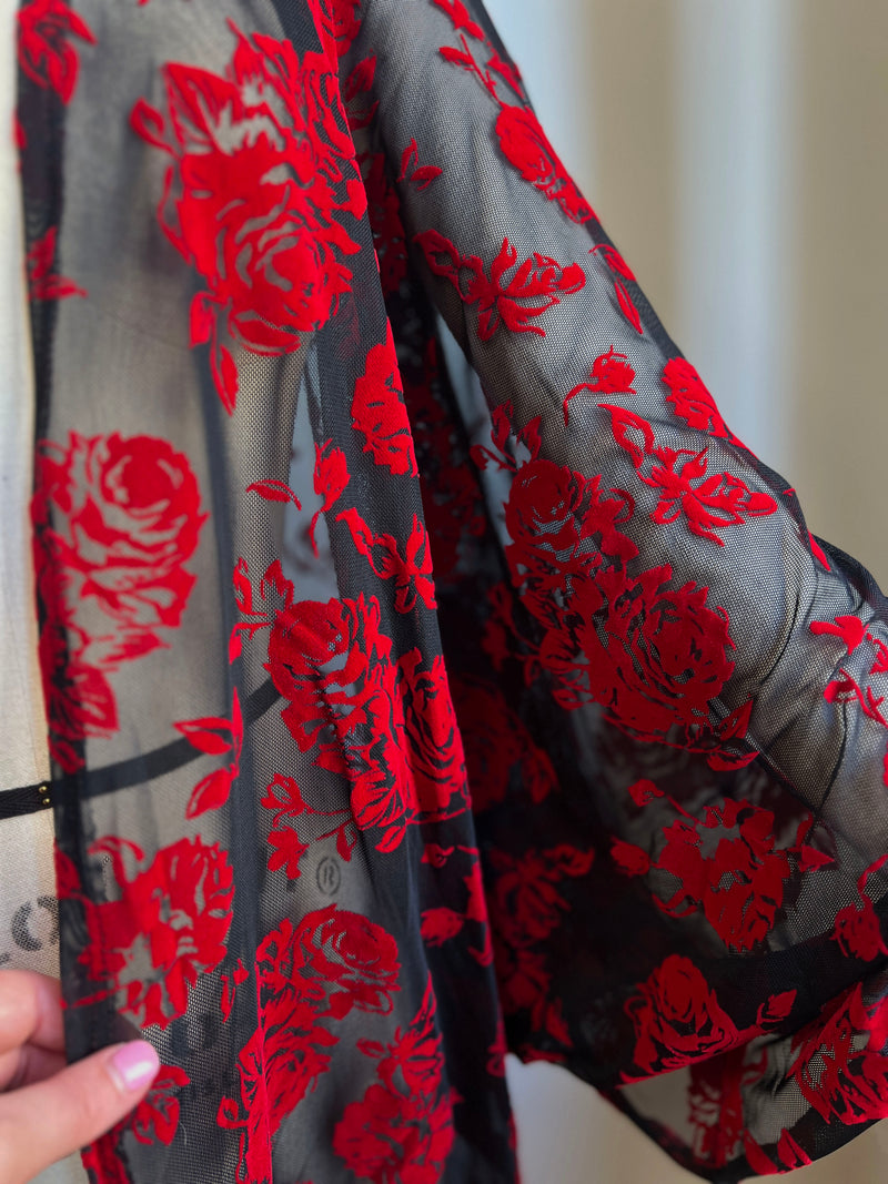 Close-up of a black mesh kimono with oversized red rose flocked design, showcasing its elegant long sleeves.