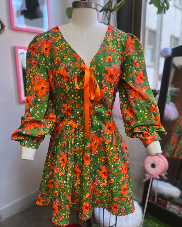 Vintage floral print mini dress with bishop sleeves, lace up front, heart buttons, in bright avocado green and orange flowers.