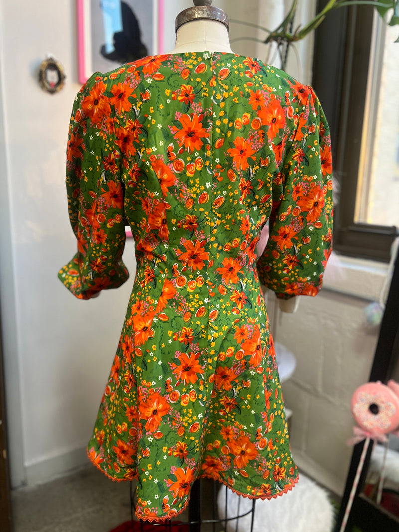 Back view of the 60s inspired mini floral dress with bishop sleeves in vintage floral print and heart buttons.