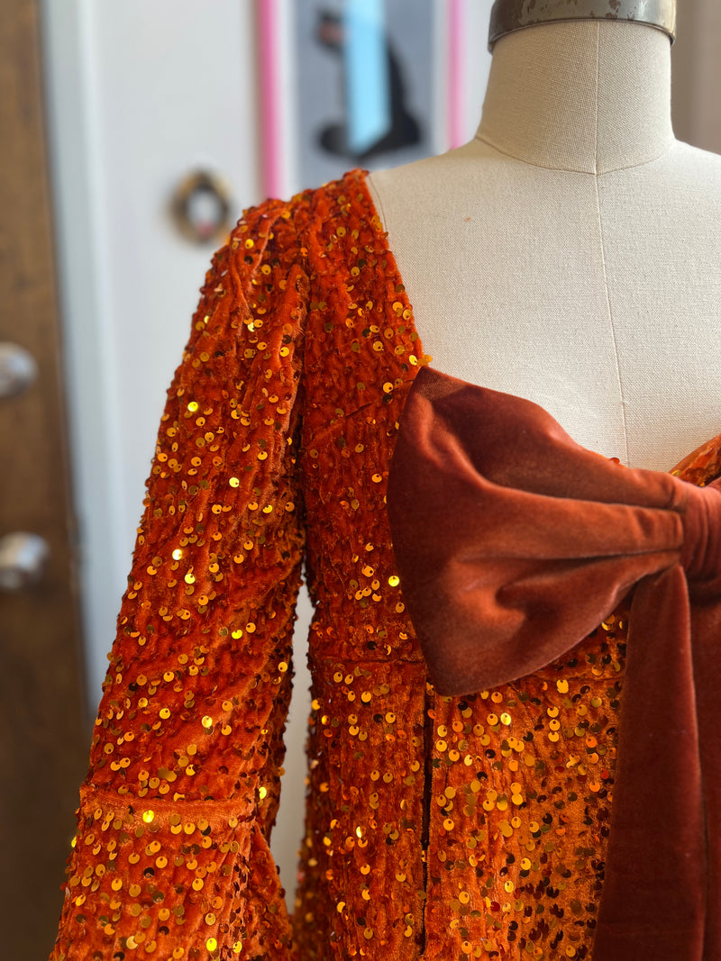 Close-up of the Priscilla 60's mini dress in pumpkin orange sequin velvet with a removable velvet bow.