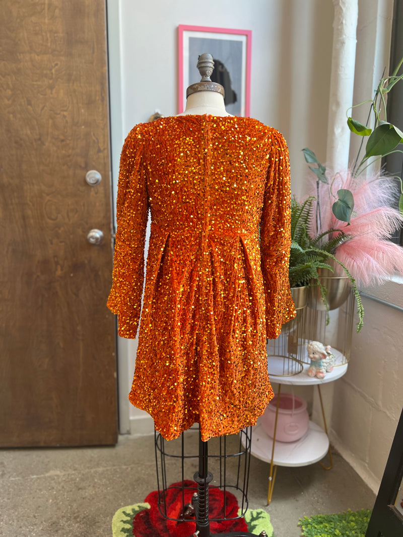 Back view of Priscilla 60's Mini Dress in pumpkin orange sequin velvet with bell sleeves and removable bow.