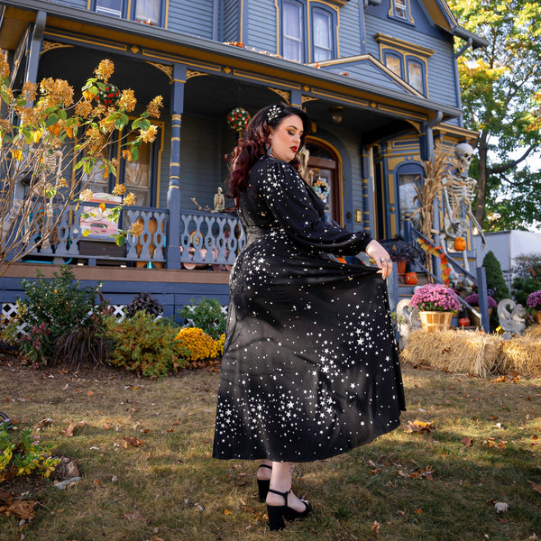 Woman in Raquel Maxi Dress with Bishop sleeves, showcasing star cluster print in a scenic outdoor setting.