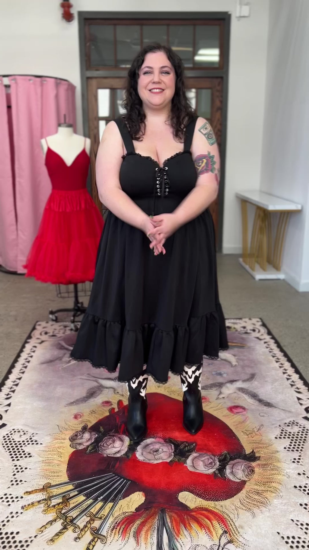 Model wearing a plus size black ponte swing dress with lace-up front and ruffles, showcasing comfortable style and pockets.